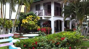 A hotel with a covered outdoor area, a pool, and lush greenery. - Cabinas Marielos (Tamarindo)
