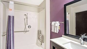 A bathroom with a shower, a sink, a mirror, and a towel rack.
