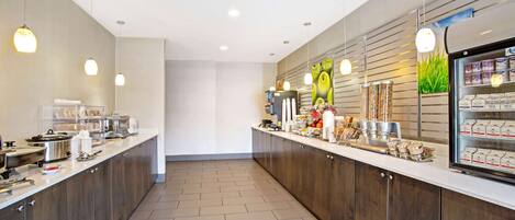 Una cocina moderna con una encimera larga, equipada con varios electrodomésticos y un refrigerador.