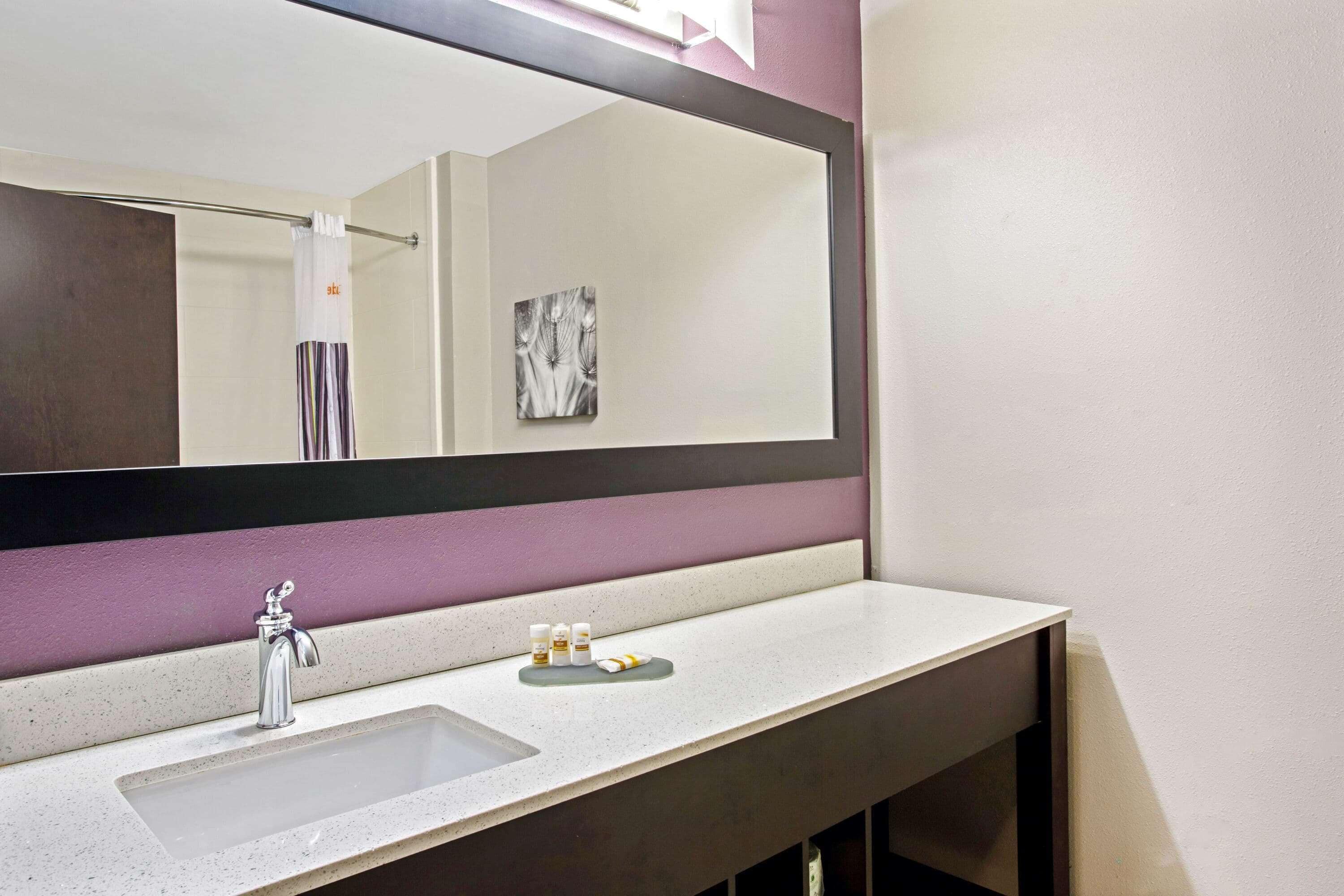 A bathroom with a large mirror, a sink, and a vanity with a countertop.