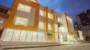 Un bâtiment moderne avec une façade jaune, de grandes fenêtres et une entrée bien éclairée.