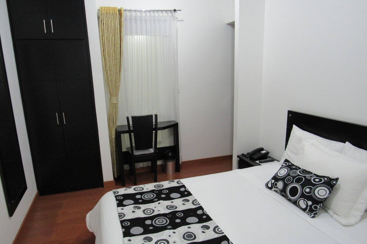 Habitación de hotel con cama, escritorio, silla y armario.