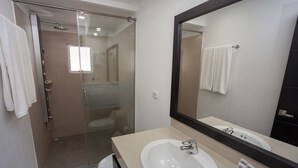 Une salle de bain moderne avec une douche à parois de verre, un lavabo blanc et un grand miroir.