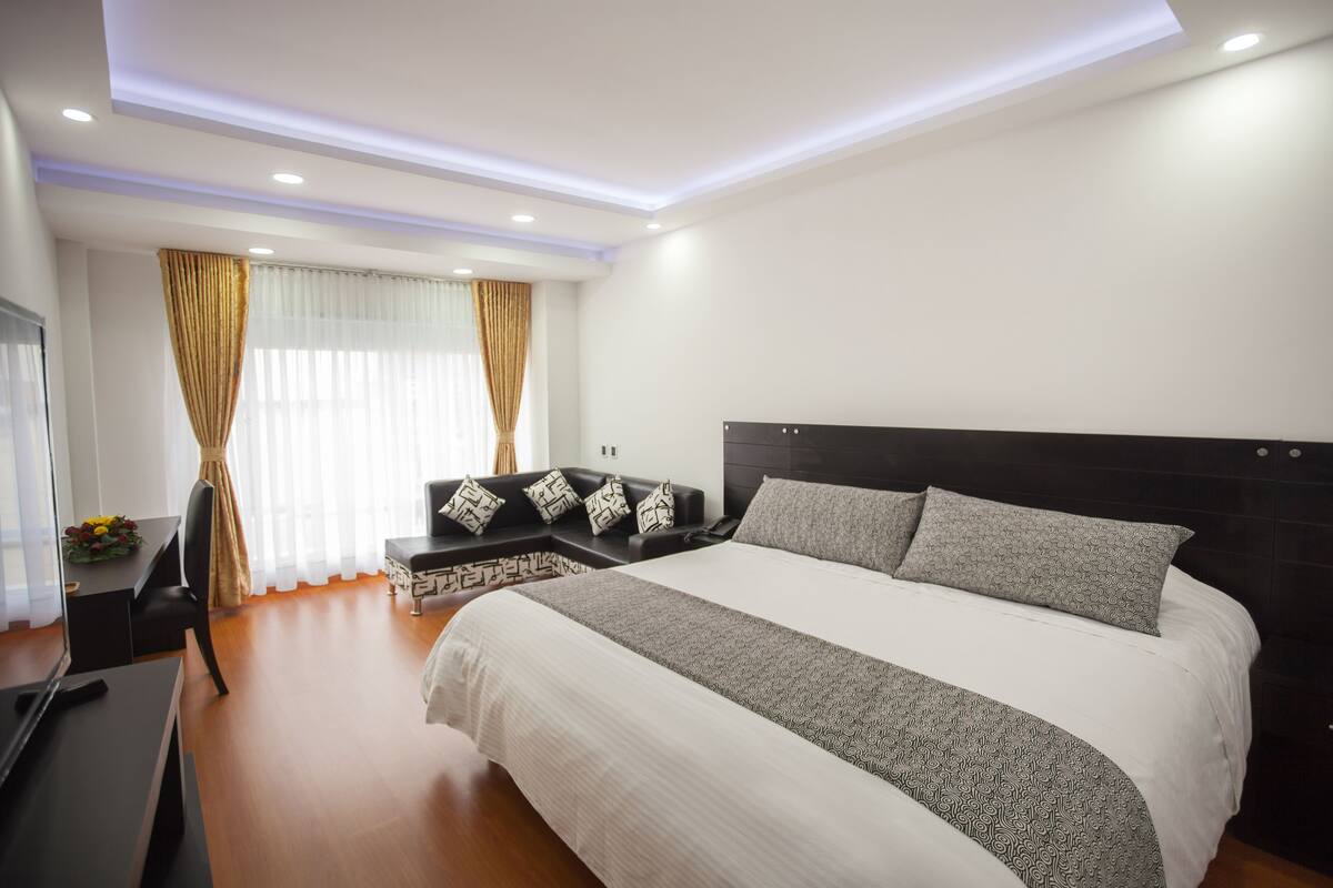 Una habitación de hotel moderna con una cama grande, un escritorio y un sofá.