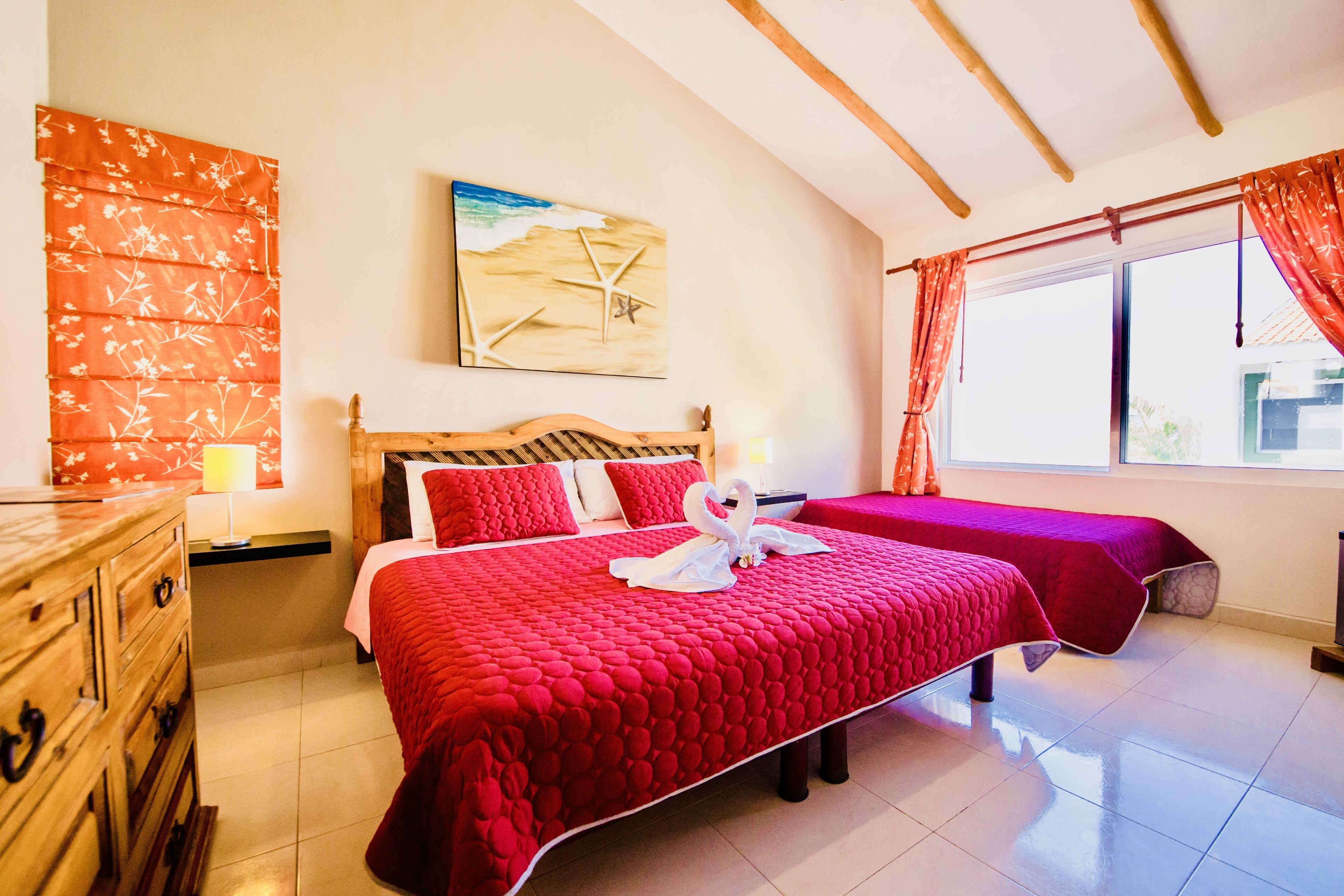 Un dormitorio con una cama grande, un aparador de madera, un cuadro y una ventana con cortinas.