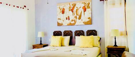 A hotel room with a large bed, two bedside tables, a chair, and a painting on the wall.