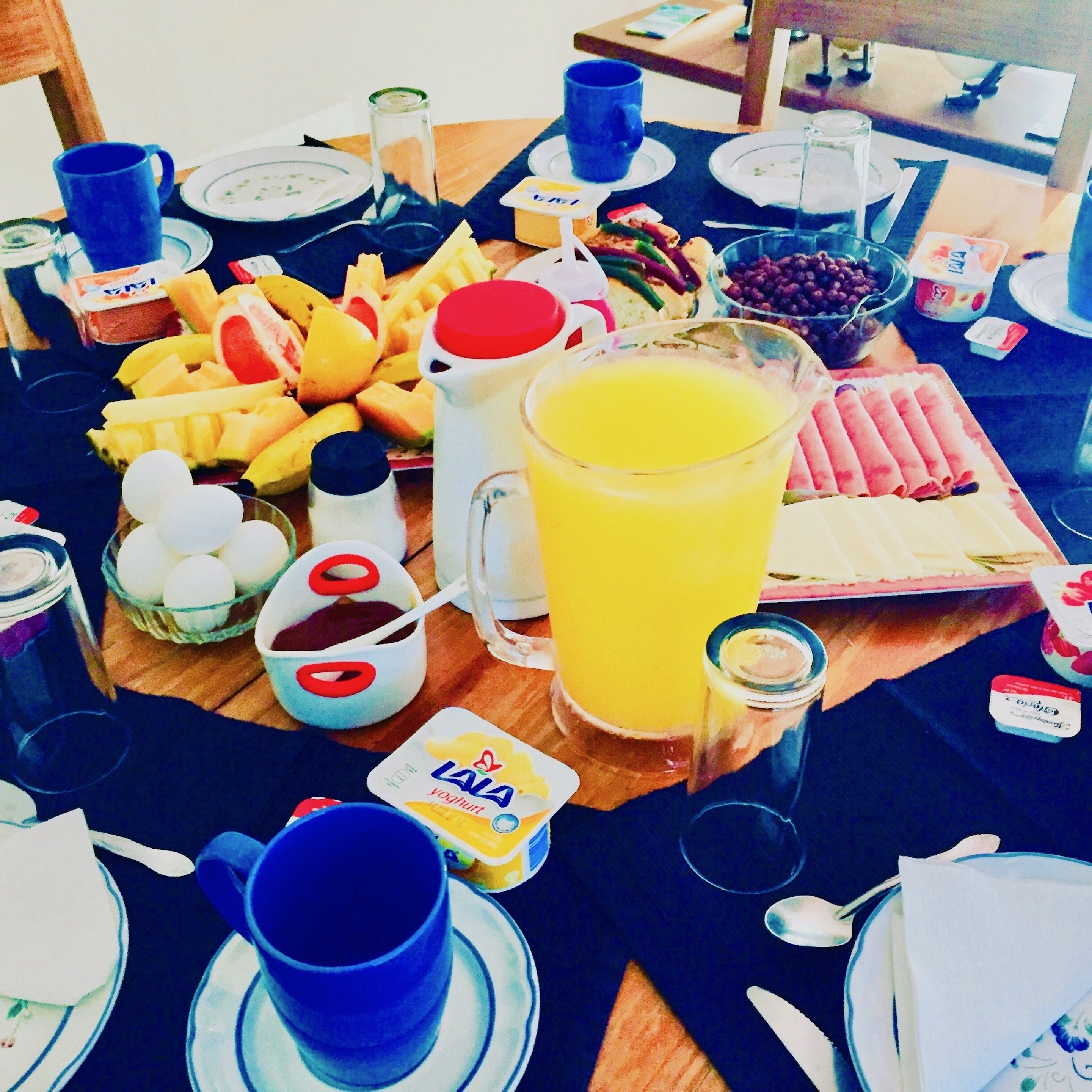 Una mesa de desayuno con diversos alimentos, bebidas y acompañamientos.