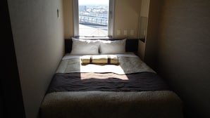 Una habitación de hotel estrecha con una cama, una ventana y vistas a la ciudad.