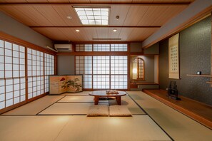 A traditional Japanese room with tatami flooring, a low wooden table, sliding doors, and a shoji screen. - Obama-onsen Hamakan Hotel (Unzen)