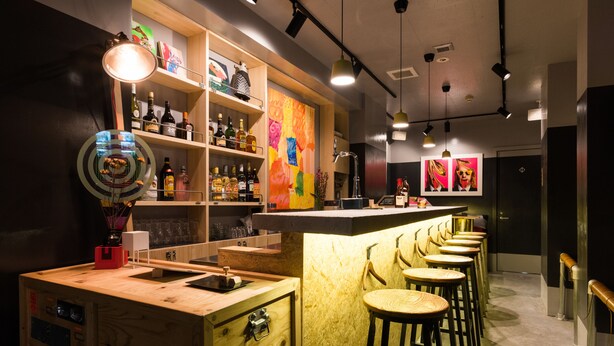 A bar area with wooden shelves, stools, and a counter. - ARTIST HOTEL - BnA HOTEL Koenji (Tokyo)