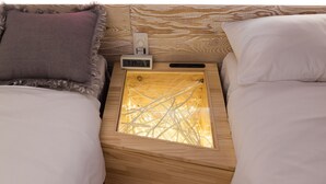 A wooden bedside table with a digital clock, a small radio, and a glass container with tangled wires. - ARTIST HOTEL - BnA HOTEL Koenji (Tokyo)