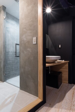 A modern bathroom with a glass shower enclosure, a large sink, and a wooden vanity.