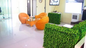 A reception area with a glass partition, a reception desk, a television, and orange chairs. - 42 Place (Bangkok)