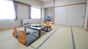 A traditional Japanese room with tatami flooring, a low table, and a television. - Hotel Saharin (Wakkanai)