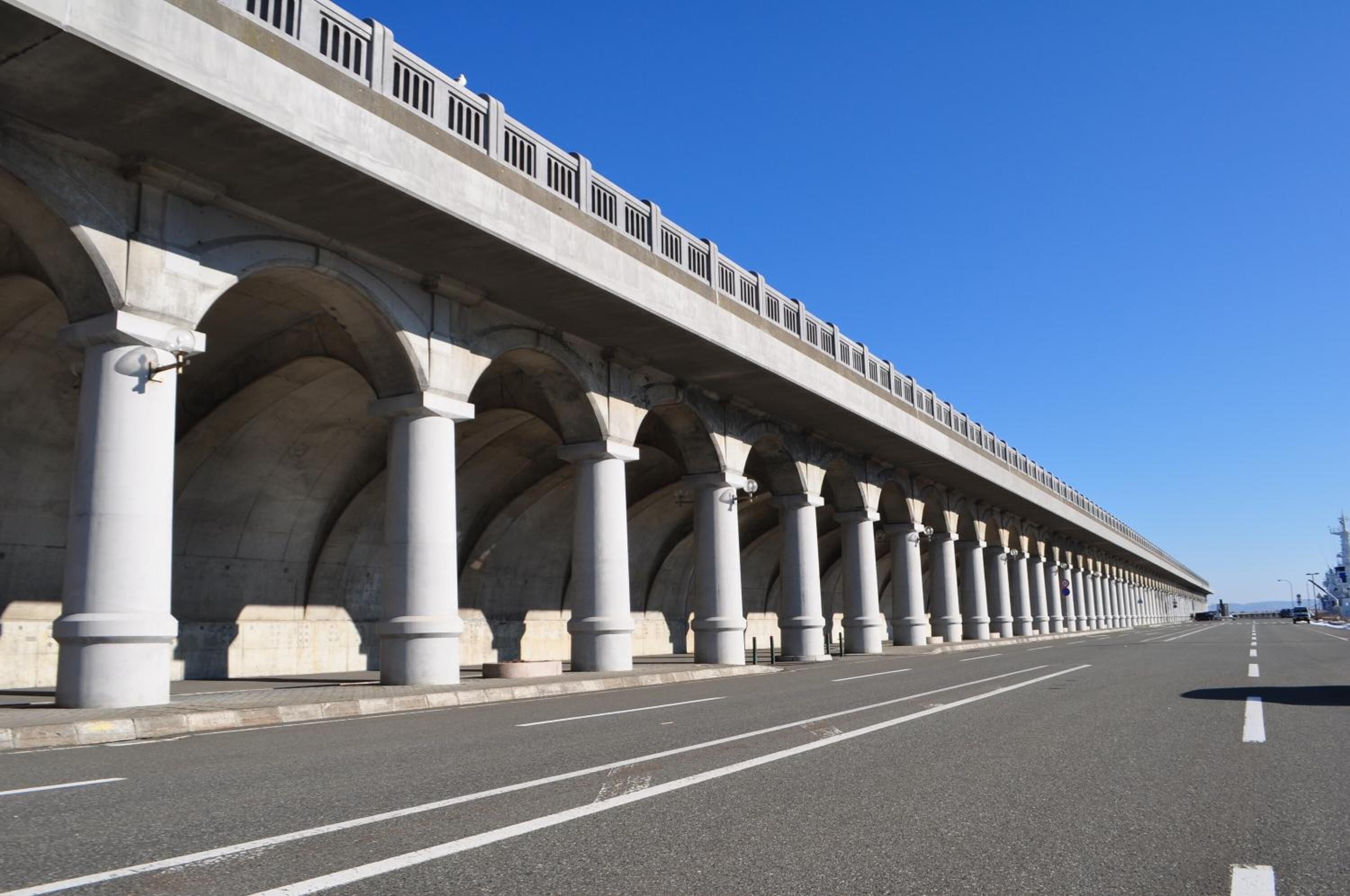 A long, covered pedestrian bridge with multiple arches and a metal railing.