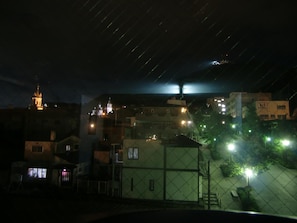 A nighttime view of a residential area with buildings, a church tower, and streetlights. - Hotel Hachimanzaka (Hakodate)