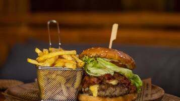 A burger with a bun, lettuce, and a beef patty, accompanied by a basket of French fries.