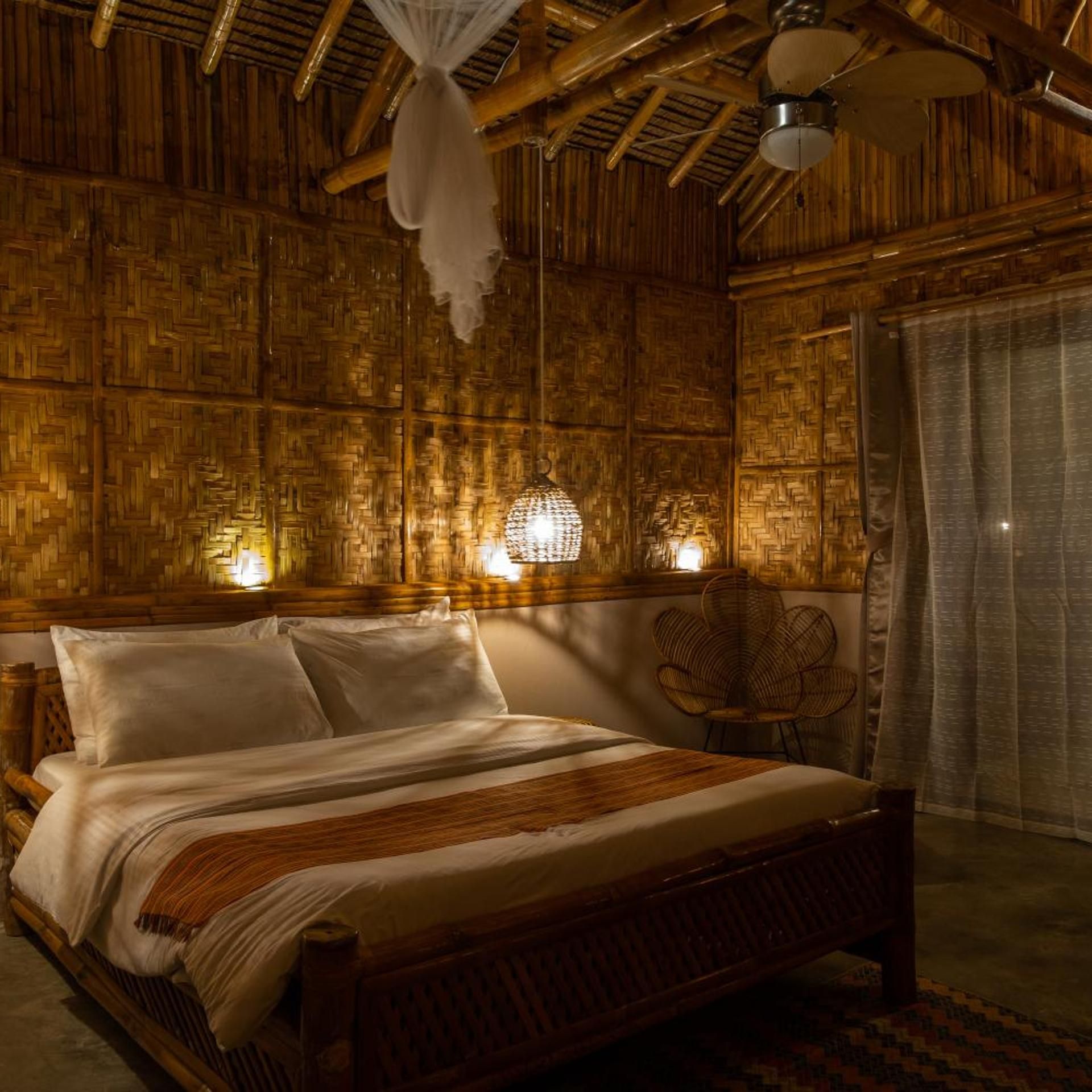 A room with a bed, a chair, and a wall with a woven pattern.