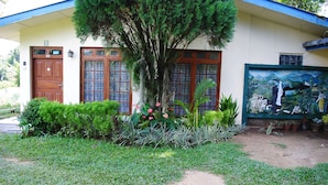 A building with a large tree in front, a mural on the right, and a well-maintained garden. - Relaxed Style of Stay (Kandy)