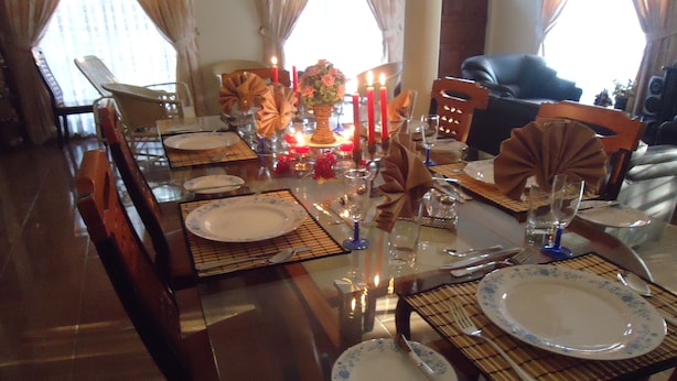 A dining table set with plates, cutlery, and candles, surrounded by chairs. - Relaxed Style of Stay (Kandy)