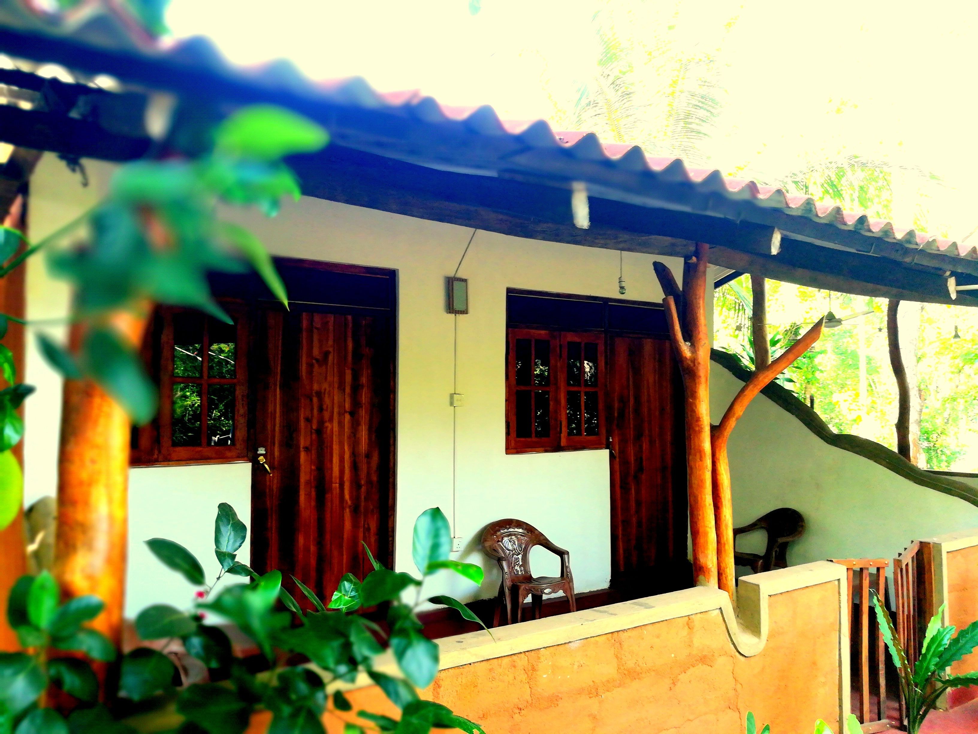 A wooden house with two windows and a covered porch.