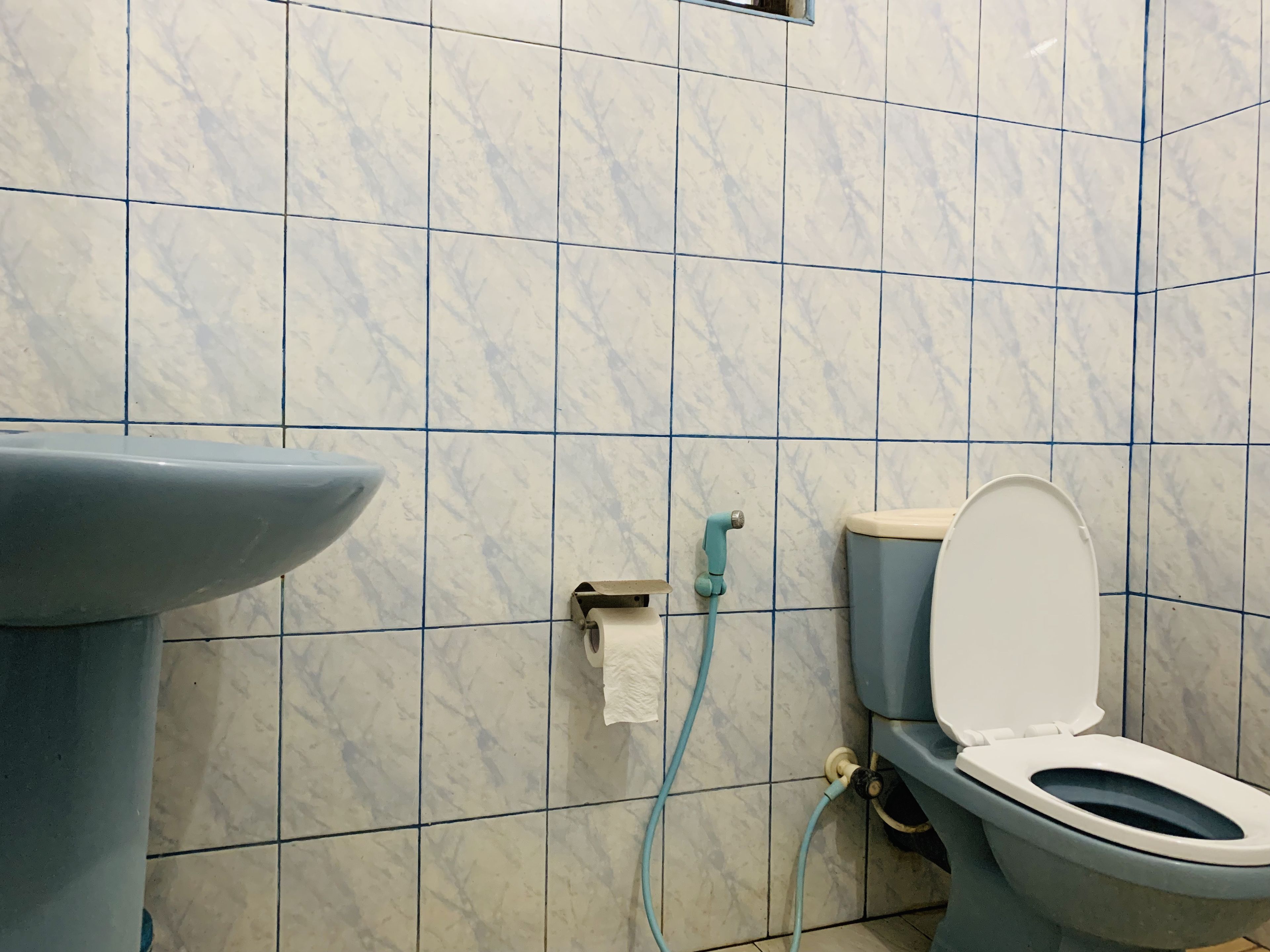 A bathroom with a toilet, sink, and tiled walls.
