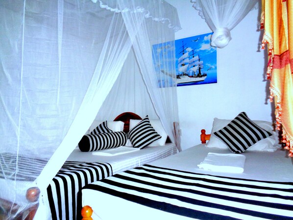 A bed with a striped bedspread, white bedding, and a canopy. There is a picture on the wall. - Sisira Natural Lodge (Sigiriya)