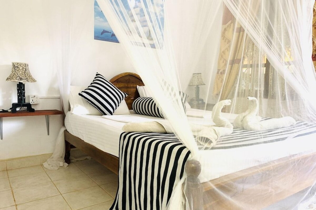 A bed with a canopy, a nightstand with a lamp, and a swan decoration.