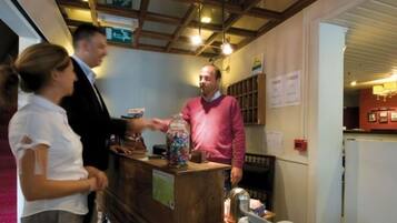 Un espace d’accueil avec un comptoir en bois, un bocal rempli de bonbons et un panneau accroché au mur.