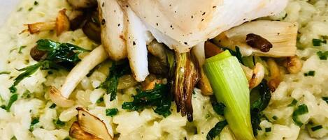Ein Gericht mit pochiertem Fisch auf Risotto mit Pilzen und Lauch.