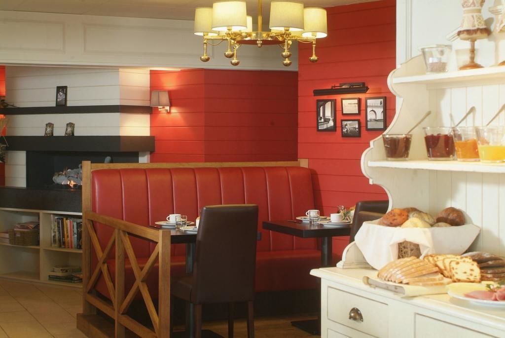Un restaurant chaleureux avec des banquettes rouges, un lustre et une variété de produits de boulangerie exposés sur des étagères.