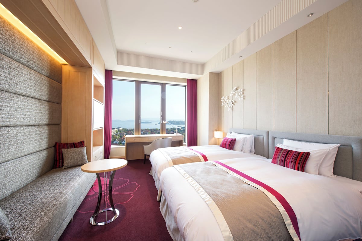 Habitación de hotel con una cama grande, un escritorio y vistas a la ciudad.
