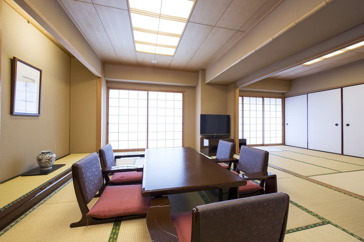 Una habitación japonesa tradicional con suelo de tatami, una mesa baja de tatami y sillas de madera.