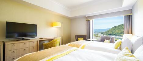 A hotel room with two beds, a TV, a desk, and a view of a cityscape.