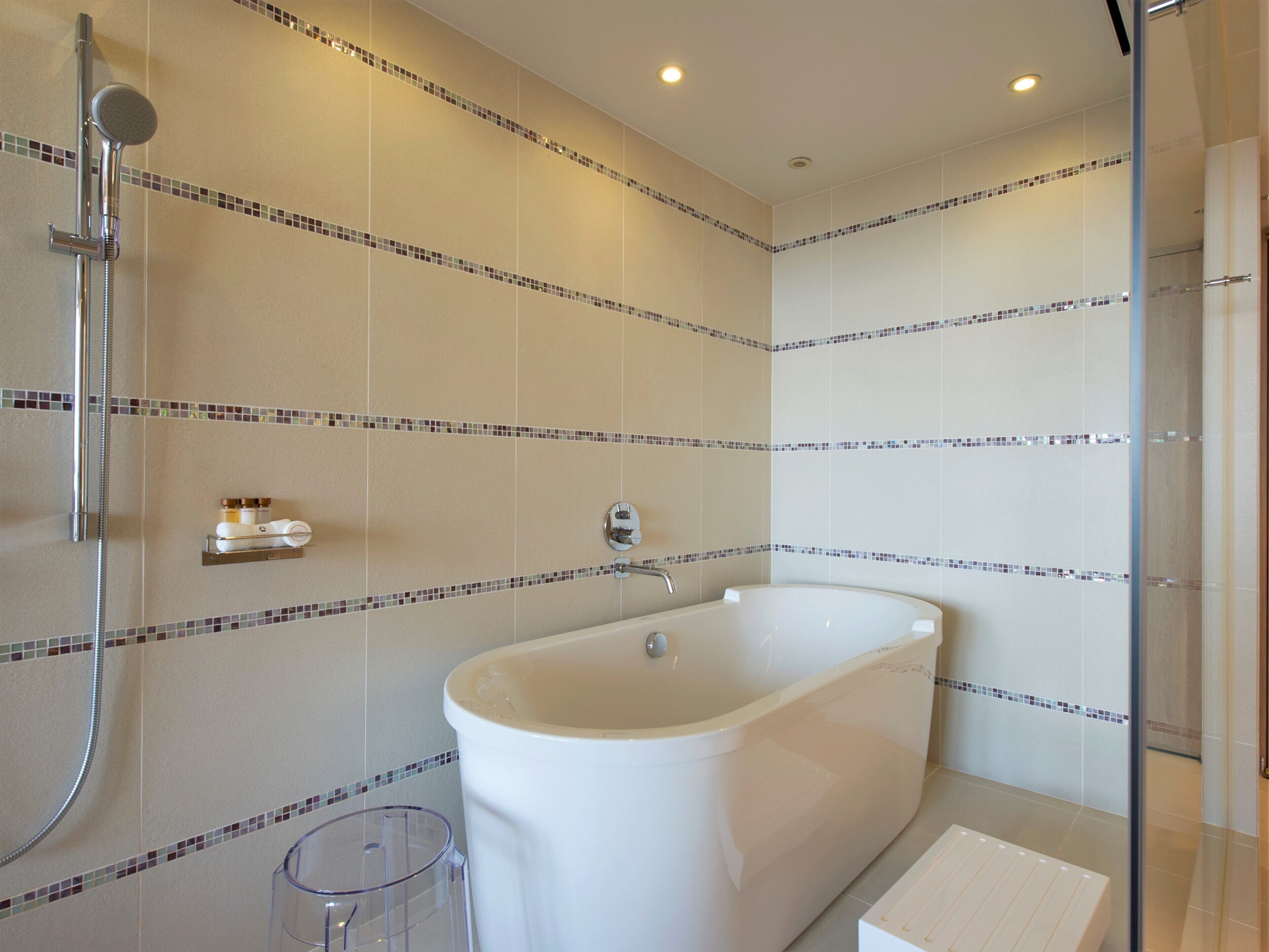 Un baño moderno con una bañera independiente, cabina de ducha con paredes de vidrio y un pequeño cubo de basura.