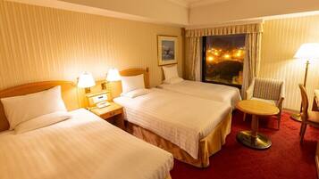 A hotel room with two beds, a small round table, and a chair.