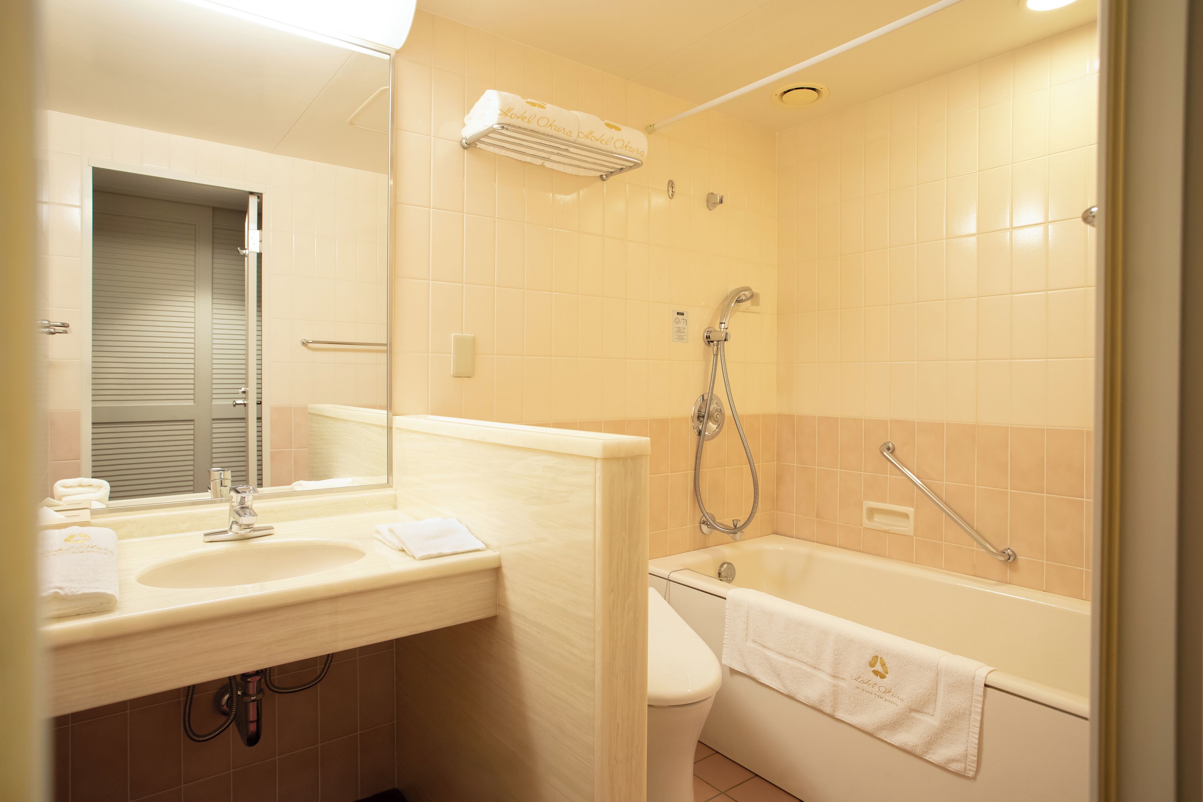 A bathroom with a sink, mirror, toilet, and bathtub.