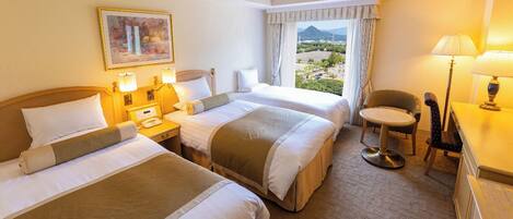 A hotel room with two beds, a desk, a chair, and a window with a mountain view.