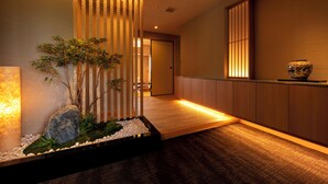 A modern interior with a reception desk, a decorative plant arrangement, and a traditional vase. - Hotel Okura JR Huis Ten Bosch (Sasebo)