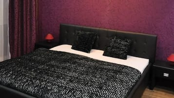 Un dormitorio moderno con una cama grande, cabecera oscura y paredes moradas.