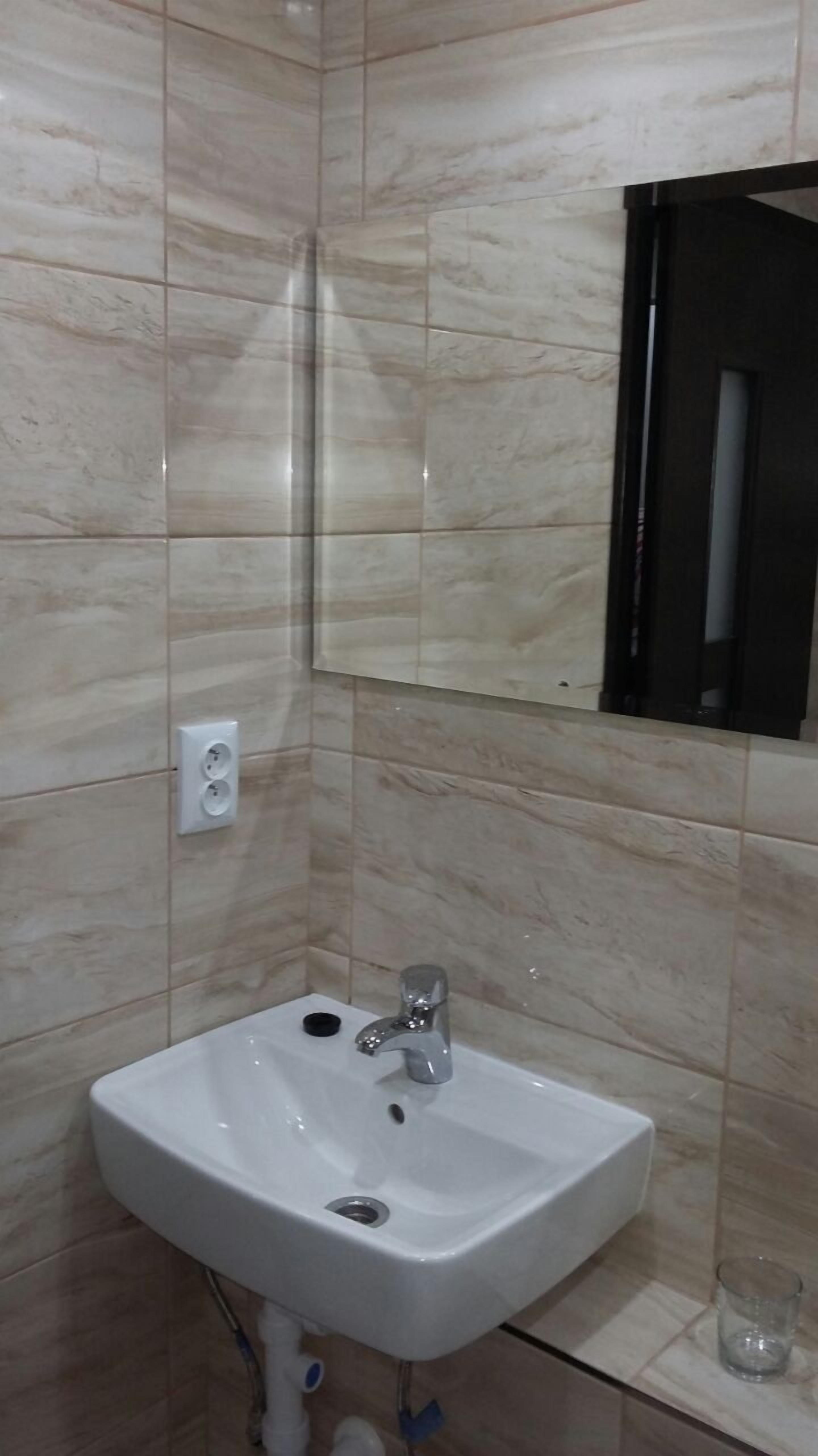 A bathroom with a white sink, a mirror, and tiled walls.