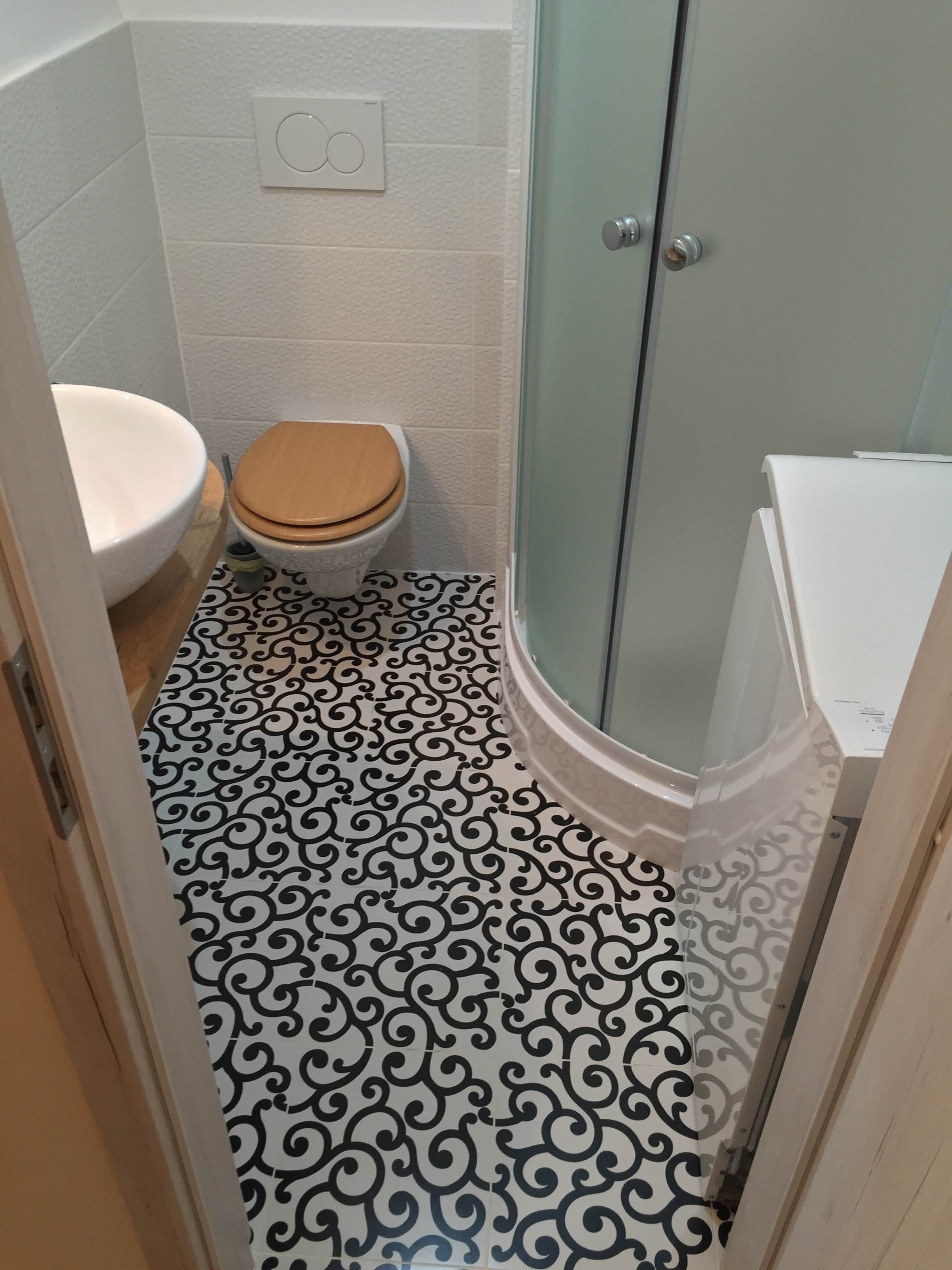 Et badeværelse med toilet, brusebad og håndvask.