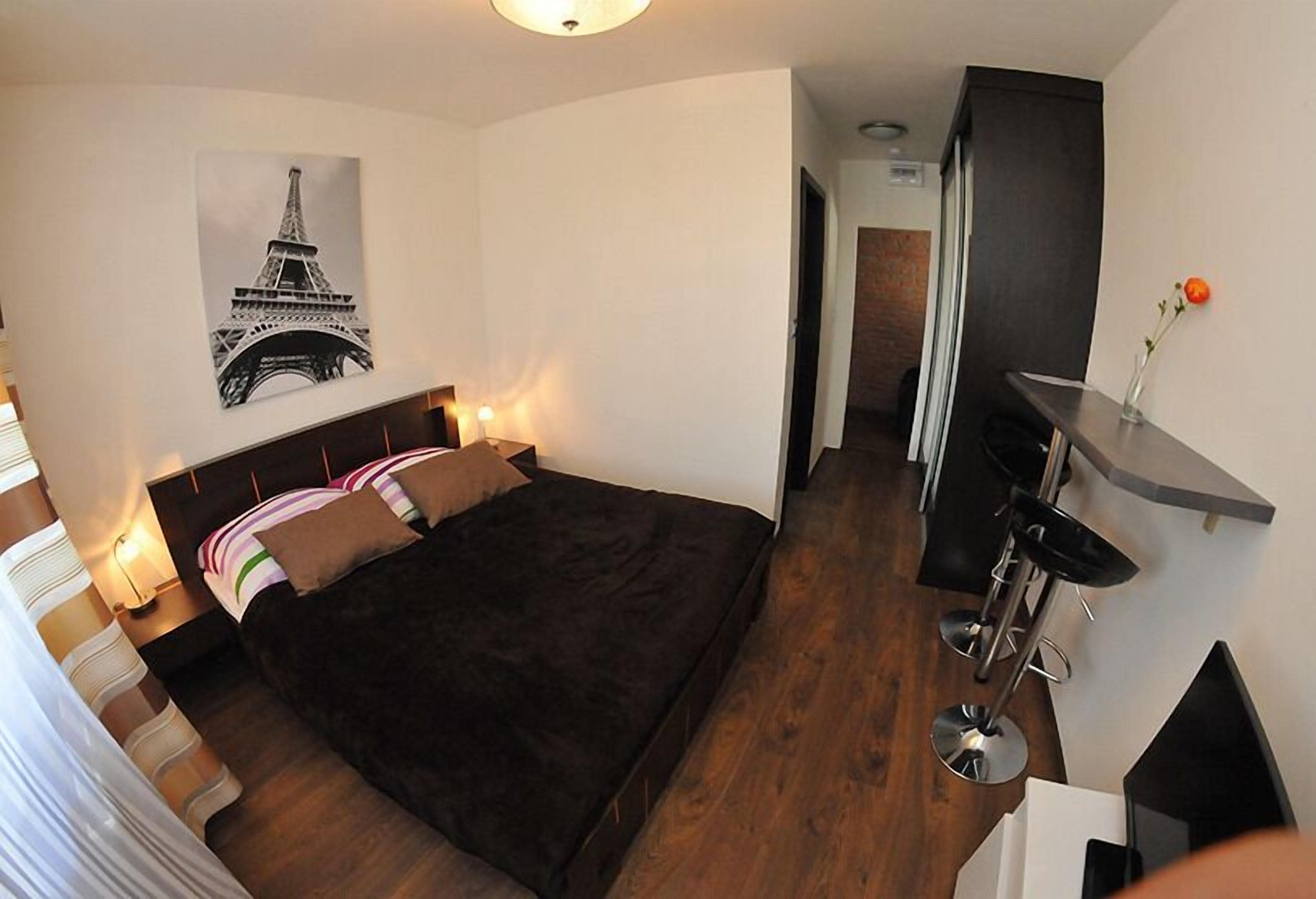 A bedroom with a bed, bedside tables, a desk, and a chair.