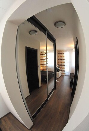 A modern hotel room with a large mirror, a bed, a desk, and a wardrobe. - Apartmany Šariš (Prešov)