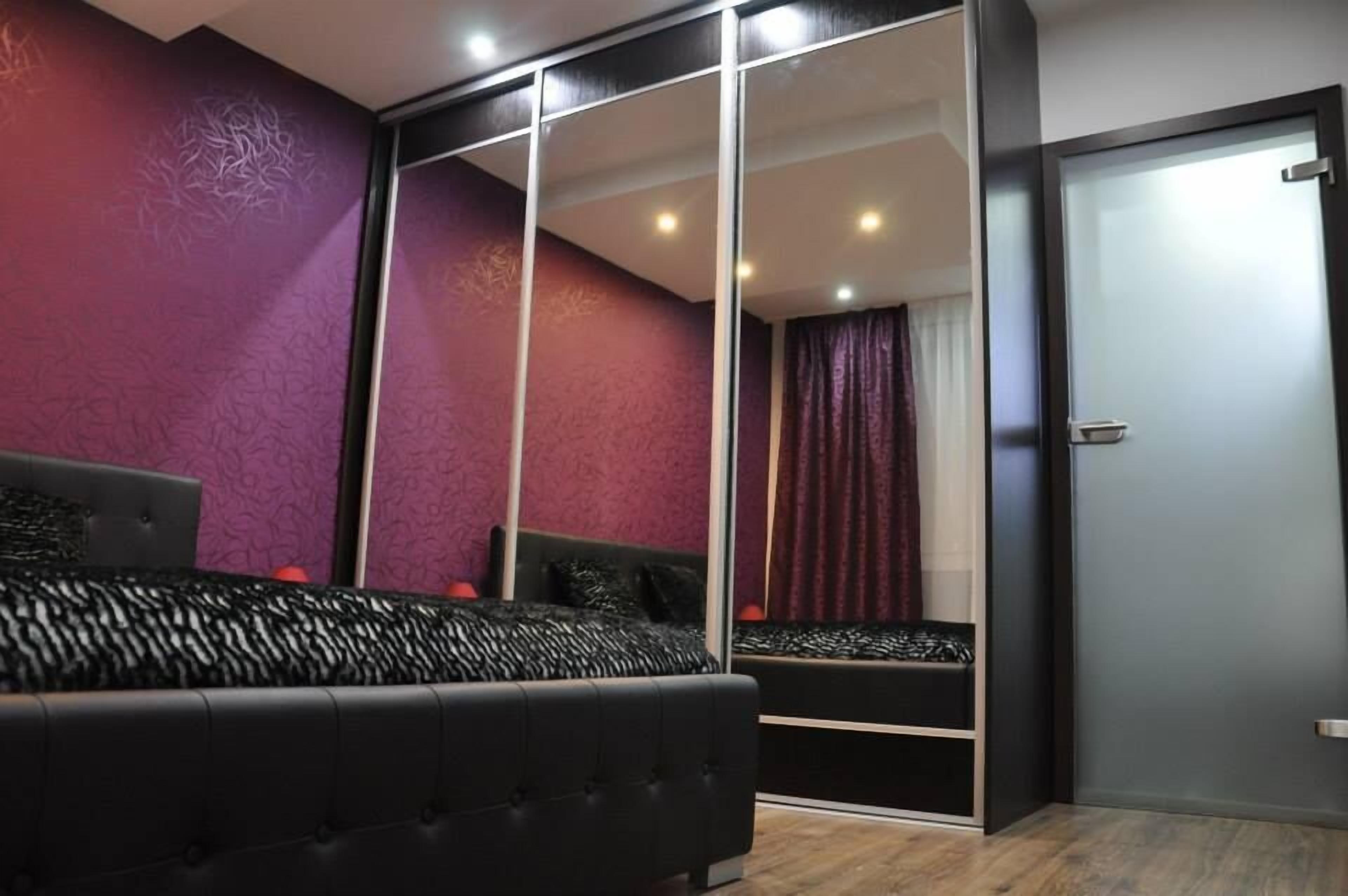 A bedroom with a large mirror, a bed, and a wardrobe.