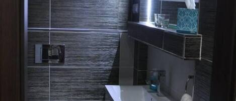 Un baño moderno con inodoro, lavabo y espejo.