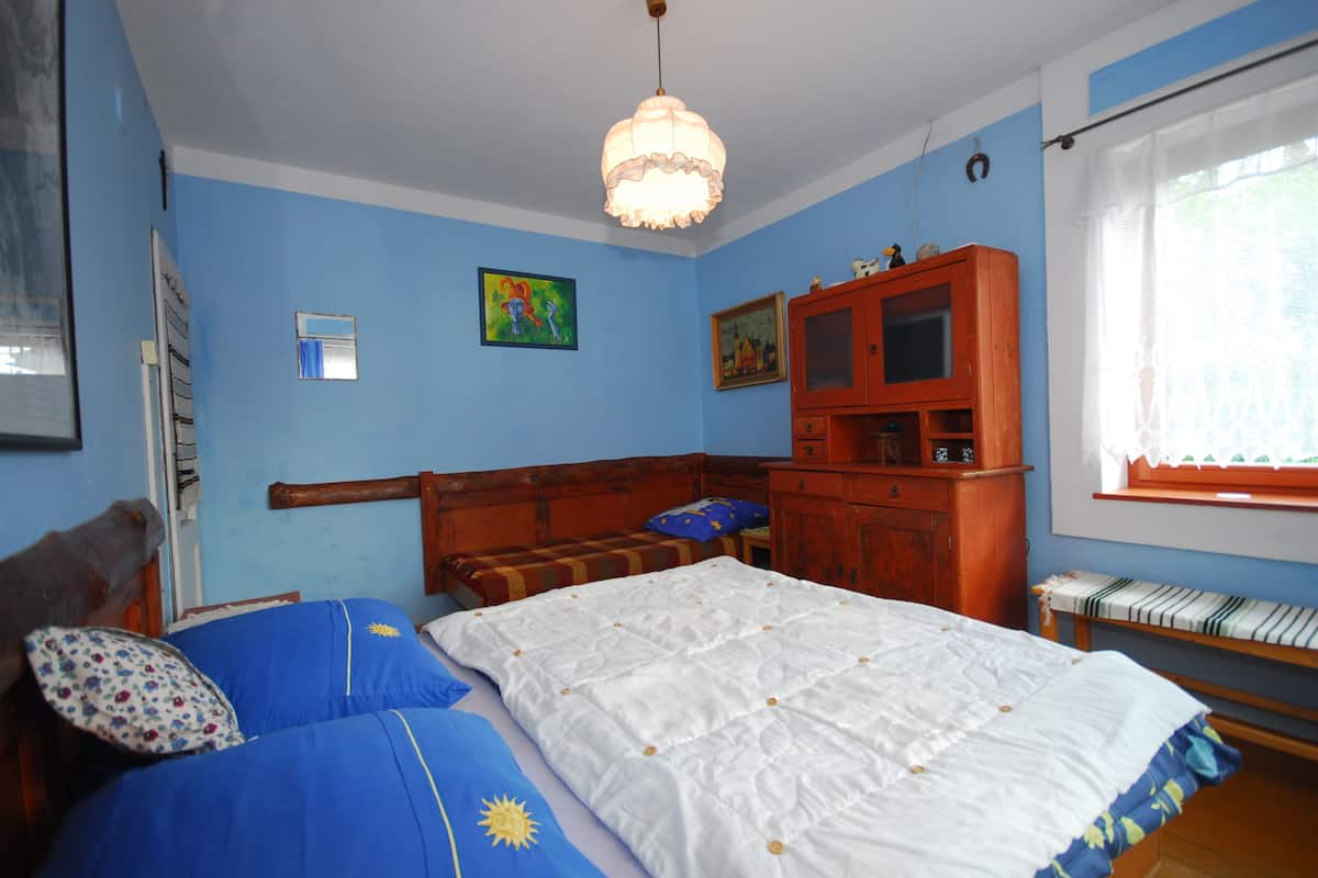 Un dormitorio con cama, cabecera de madera, armario y ventana con cortinas.