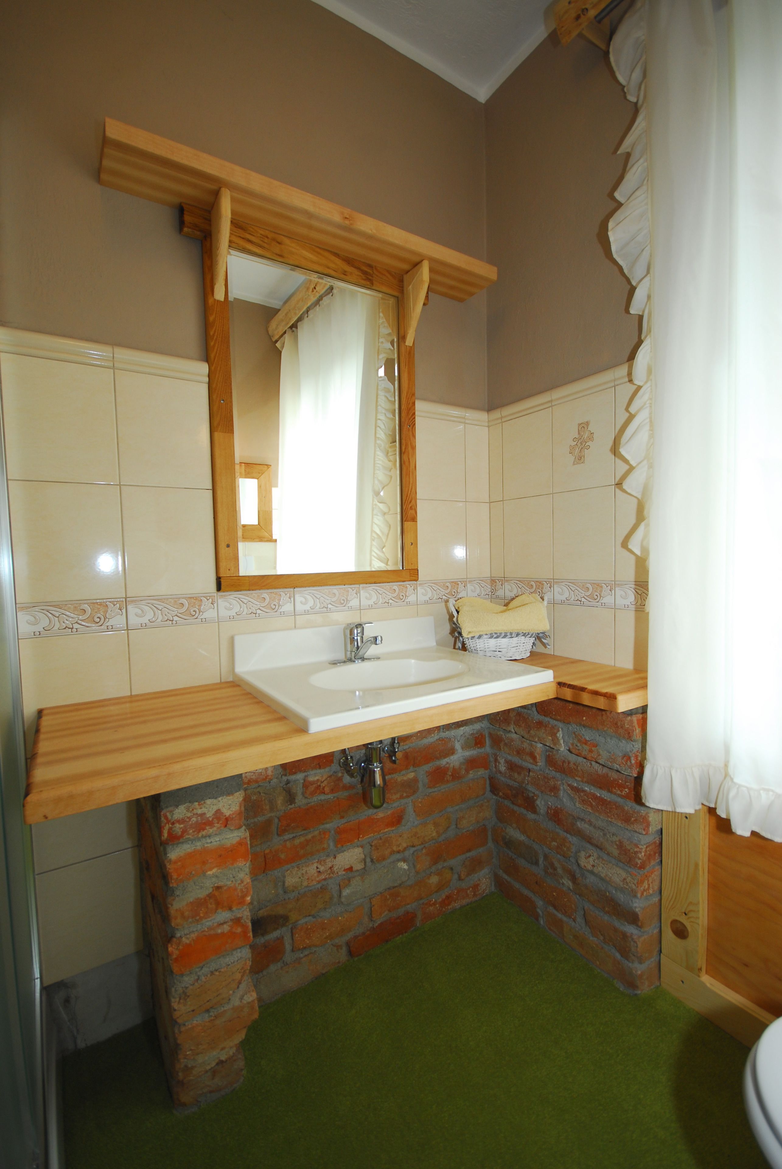 A bathroom with a wooden vanity, a white sink, and a mirror.