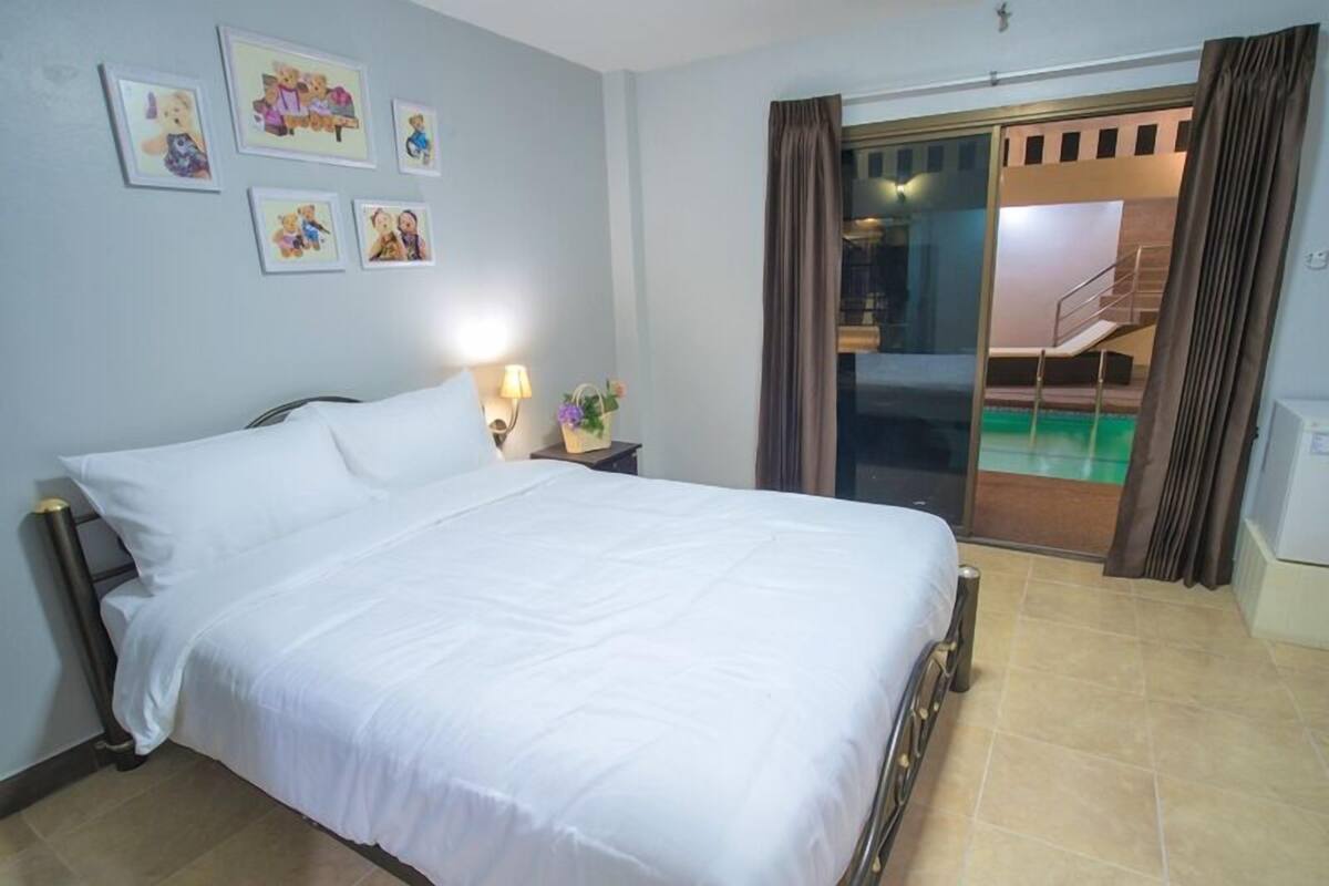 A hotel room with a bed, a nightstand, a lamp, and a set of framed pictures on the wall.