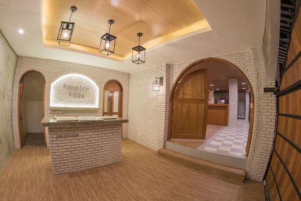 A reception area with a brick wall, a wooden reception desk, and a sign that reads "Empire Villas."